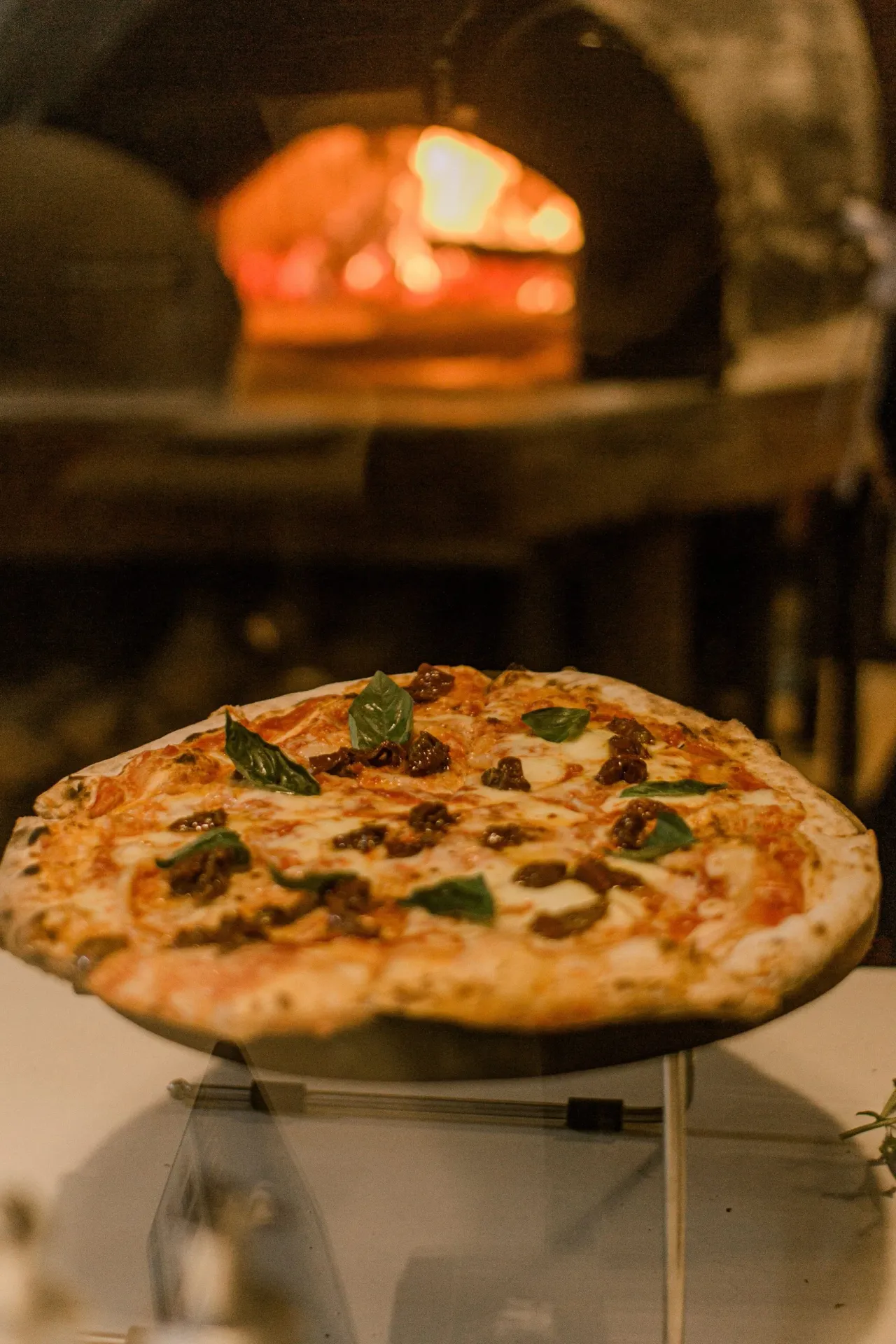 Une pizza tout juste sortie du four, devant la braise