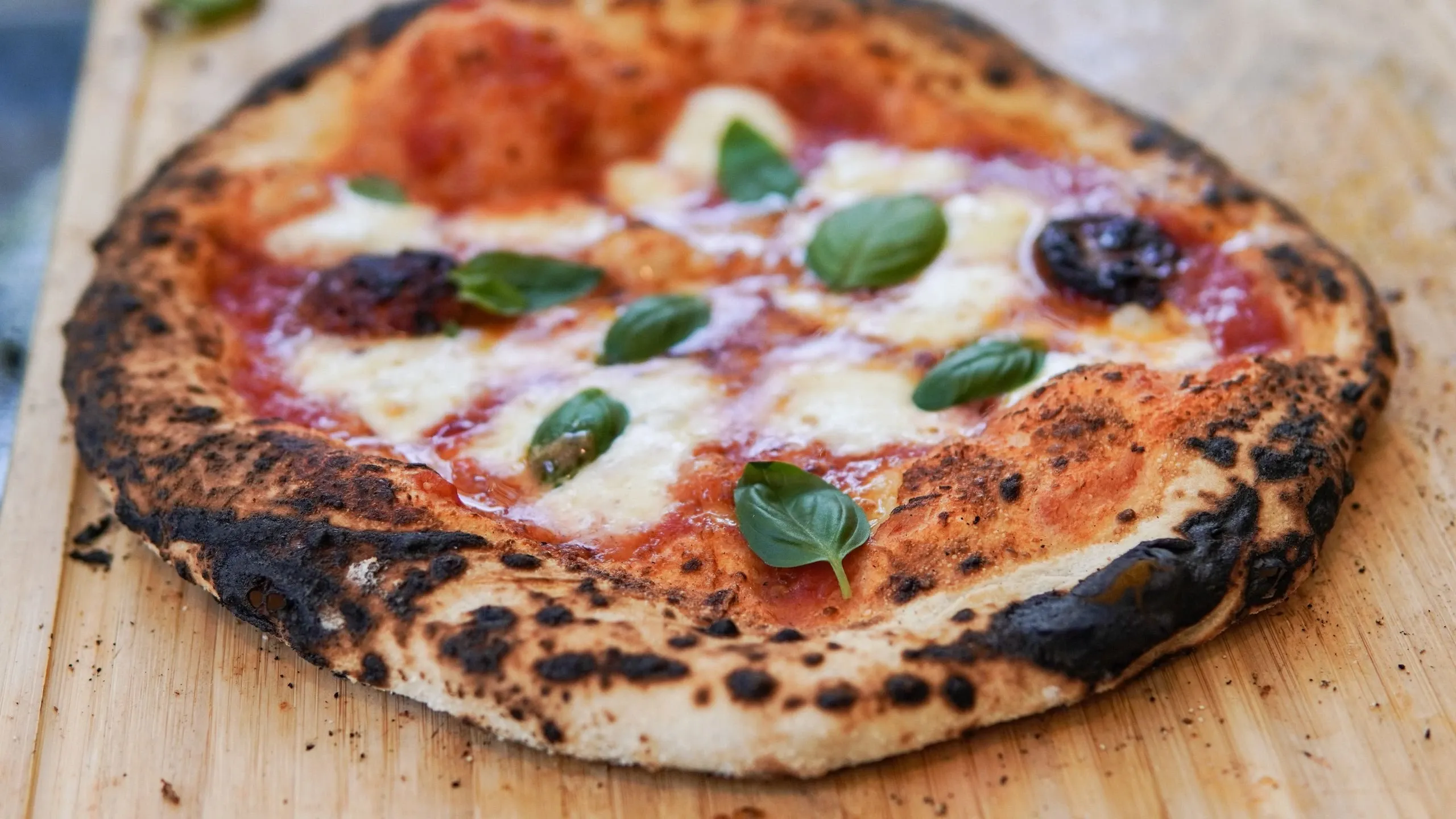 Une pizza au basilic posée sur une planche en bois